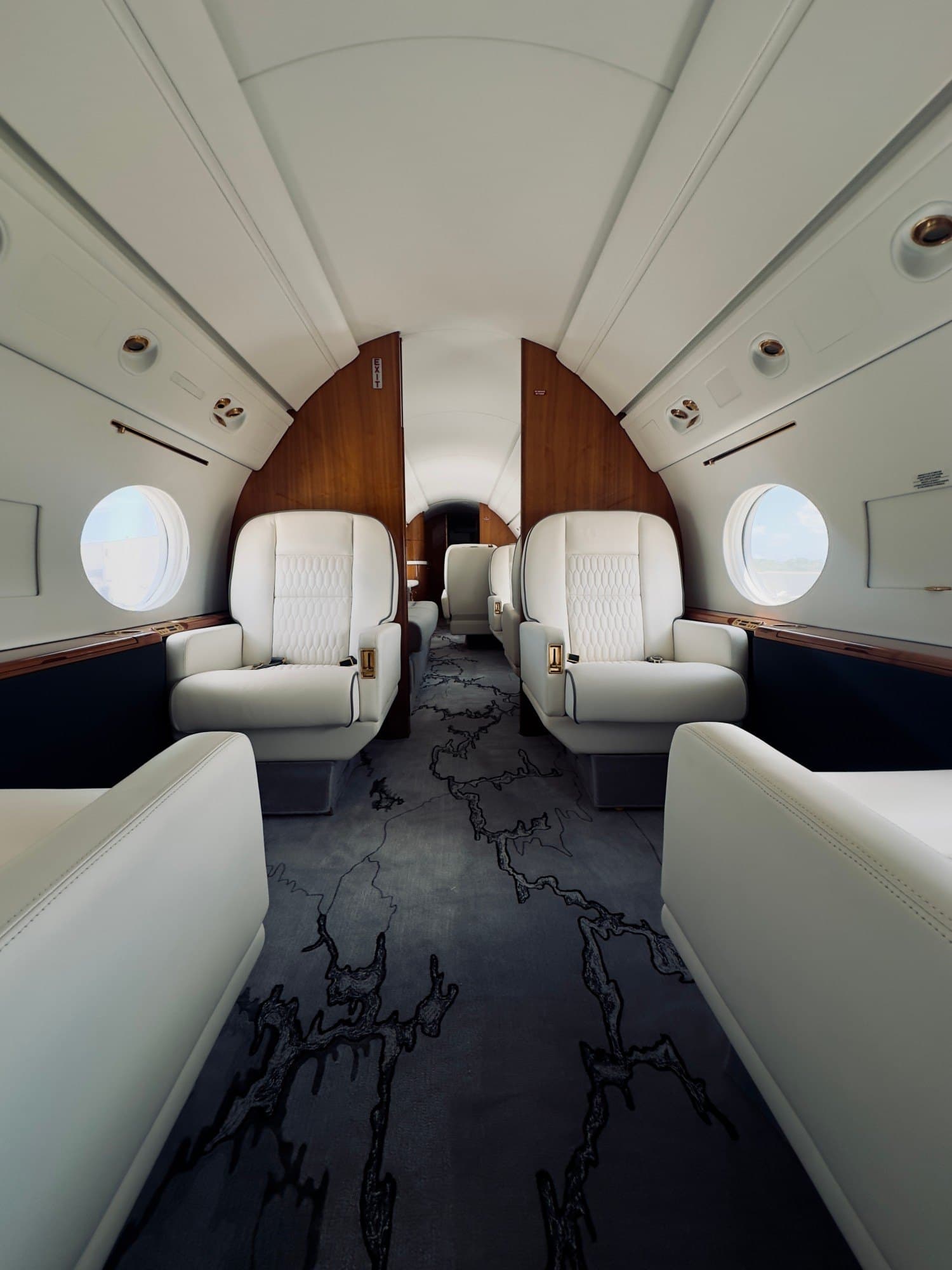 Cabina di jet privato con poltrone in pelle bianca e pannelli in legno