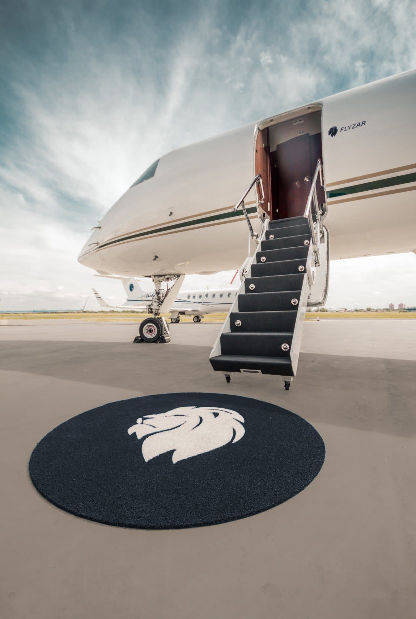 Escalerilla de un jet privado sobre la alfombra con el león de Flyzar